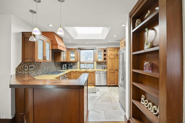 kitchen with stainless steel appliances, a skylight, a sink, custom exhaust hood, and open shelves