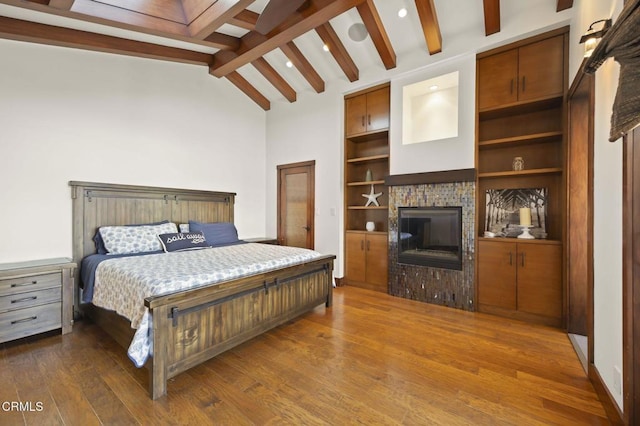 bedroom featuring vaulted ceiling with beams, a fireplace, and dark wood-type flooring