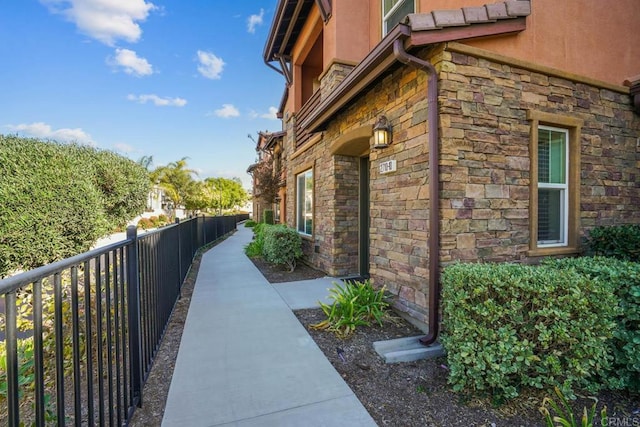 view of property exterior featuring stone siding and fence