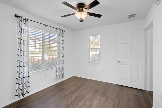 spare room featuring a ceiling fan, visible vents, baseboards, and wood finished floors