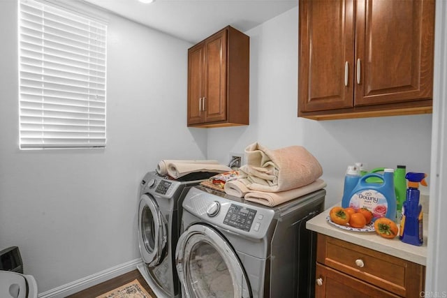 washroom featuring washing machine and clothes dryer, cabinet space, and baseboards