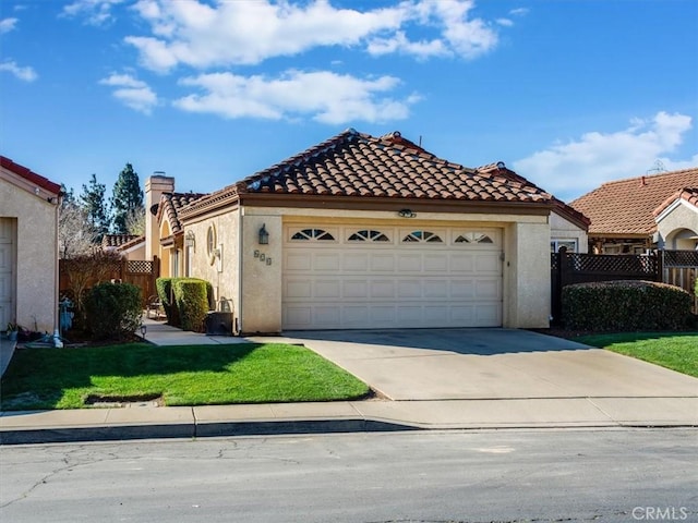 mediterranean / spanish house with driveway, a garage, a tiled roof, fence, and stucco siding