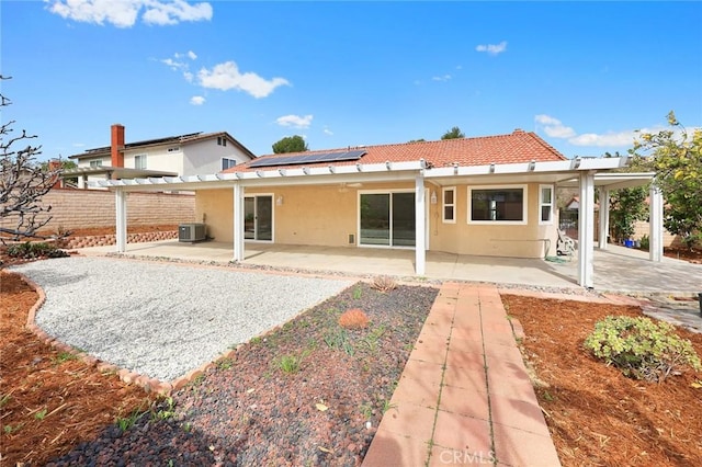 back of house featuring central air condition unit, a patio area, solar panels, and stucco siding