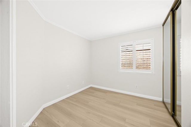 unfurnished bedroom with crown molding, light wood-type flooring, and baseboards