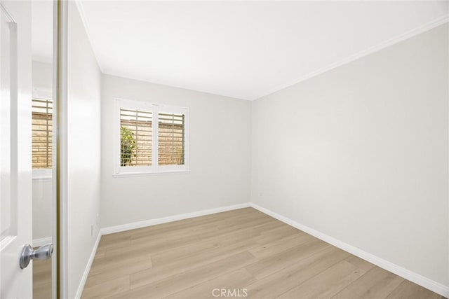 unfurnished room with light wood finished floors, baseboards, and crown molding