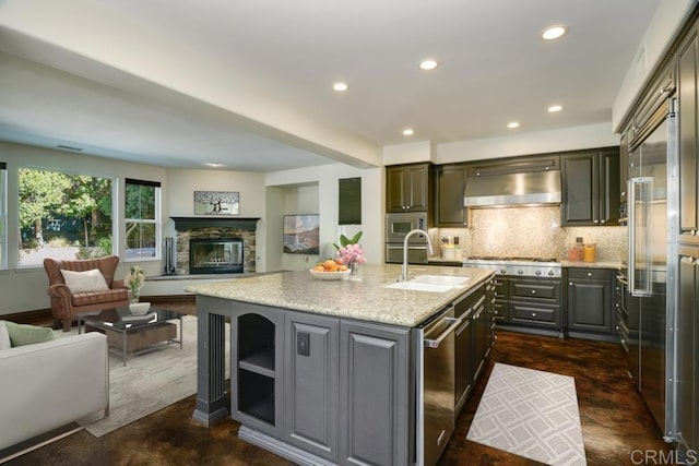 kitchen featuring backsplash, extractor fan, open floor plan, appliances with stainless steel finishes, and a sink