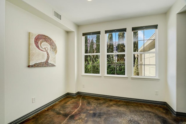 empty room featuring visible vents, concrete floors, and baseboards