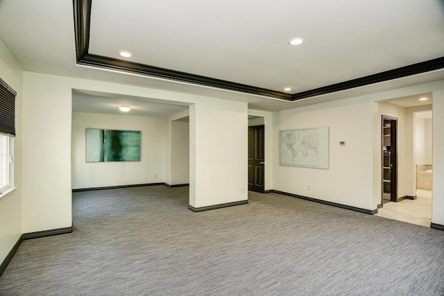 carpeted empty room featuring a tray ceiling, recessed lighting, and baseboards