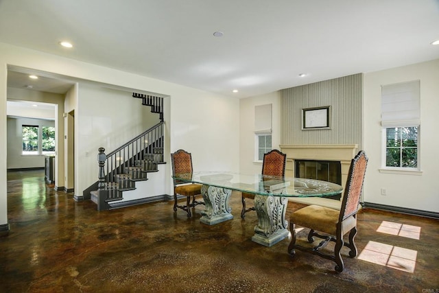 dining room featuring a glass covered fireplace, recessed lighting, stairs, and baseboards