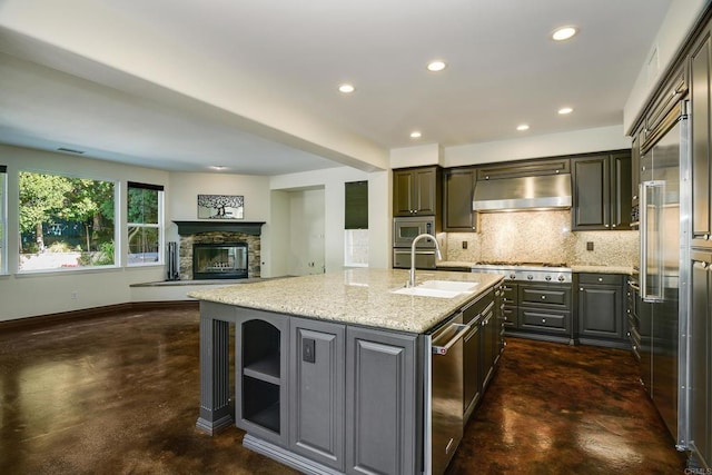 kitchen featuring ventilation hood, concrete floors, built in appliances, decorative backsplash, and a sink