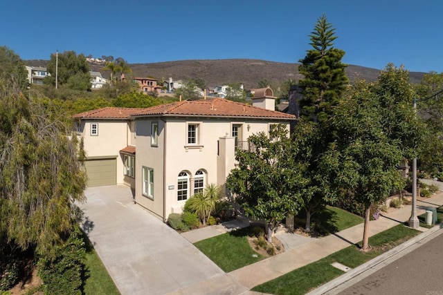 view of front of property featuring an attached garage, a tiled roof, concrete driveway, stucco siding, and a mountain view