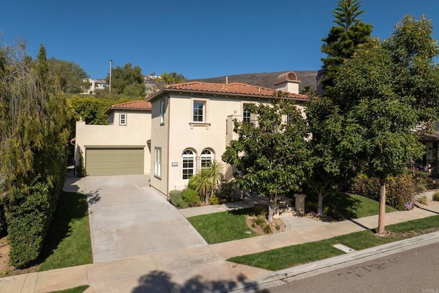 mediterranean / spanish house with a tile roof, a garage, driveway, and stucco siding