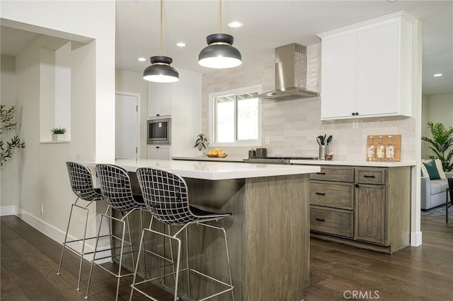 kitchen with wall chimney exhaust hood, a kitchen breakfast bar, dark wood-style flooring, stainless steel appliances, and backsplash