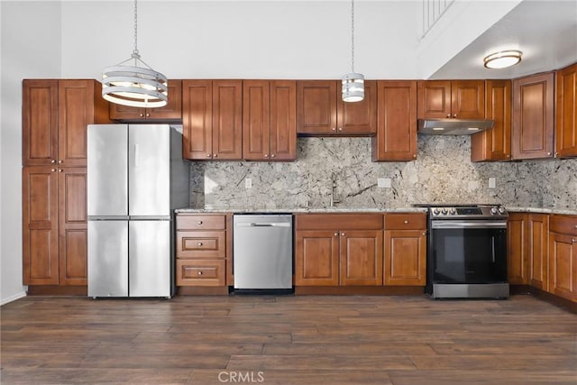 kitchen with a high ceiling, appliances with stainless steel finishes, a sink, light stone countertops, and under cabinet range hood