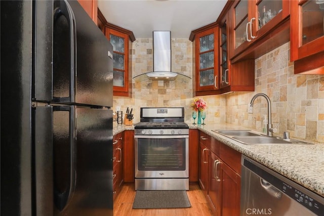 kitchen featuring wall chimney exhaust hood, light wood-style flooring, a sink, stainless steel appliances, and backsplash