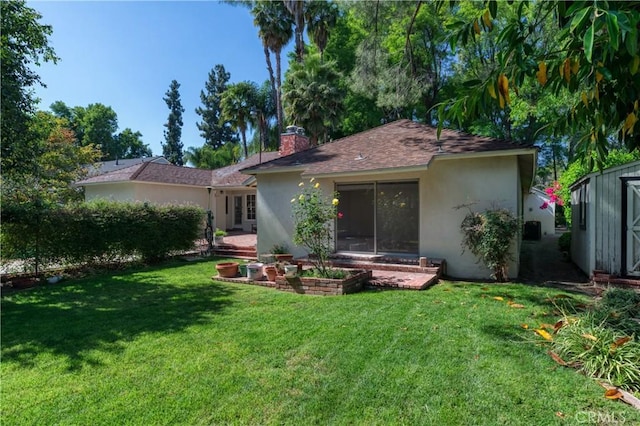 back of house featuring a yard, a chimney, and stucco siding