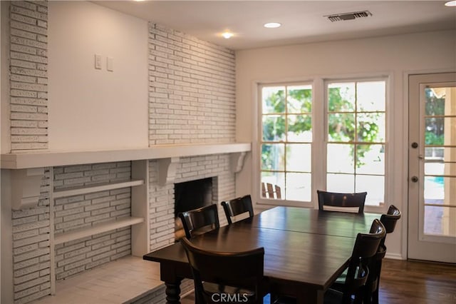 dining space featuring recessed lighting, brick wall, wood finished floors, visible vents, and a brick fireplace