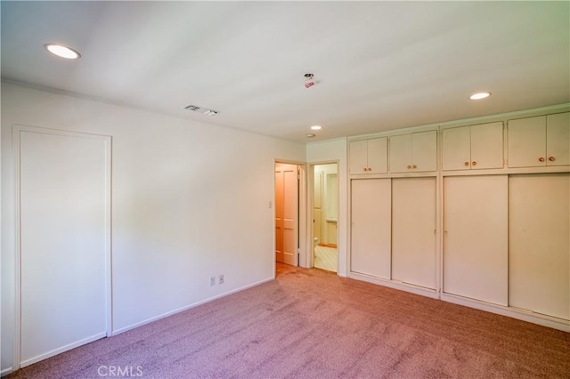 unfurnished bedroom with recessed lighting, connected bathroom, visible vents, and light colored carpet