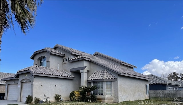 view of front of home featuring a tile roof, fence, and stucco siding