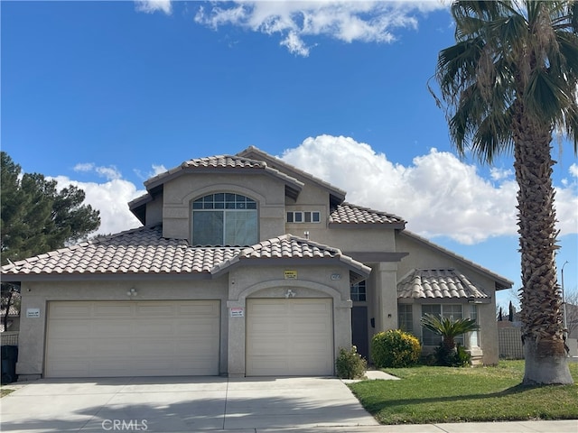 mediterranean / spanish home with stucco siding, an attached garage, driveway, a tiled roof, and a front lawn