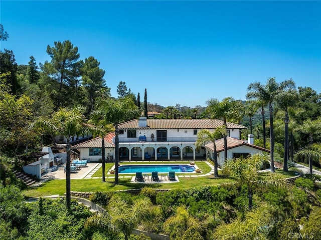 420 Inverness Dr, La Canada Flintridge, CA 91011 - back of property featuring a balcony, a patio, an outdoor pool, a tiled roof, and a lawn