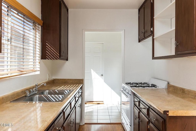 kitchen with a sink, dark brown cabinets, open shelves, gas range gas stove, and plenty of natural light