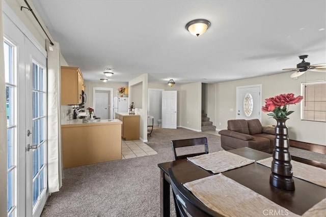 dining area featuring ceiling fan, stairway, and light colored carpet