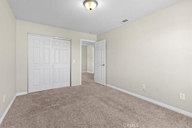 unfurnished bedroom featuring visible vents, a closet, baseboards, and carpet floors