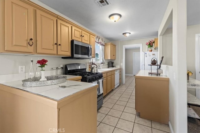 kitchen with light brown cabinets, stainless steel appliances, light tile patterned floors, a sink, and visible vents