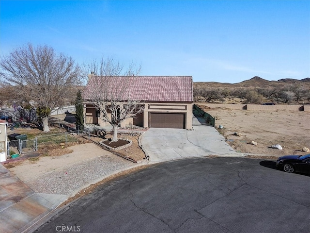 view of front of property with a tile roof, concrete driveway, an attached garage, fence, and a mountain view