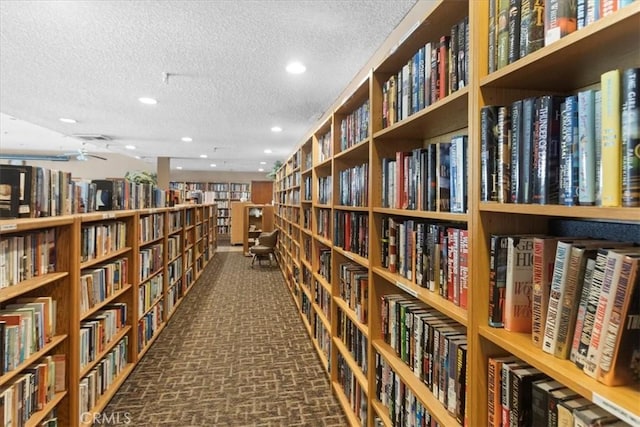 miscellaneous room with recessed lighting, brick floor, bookshelves, a ceiling fan, and a textured ceiling