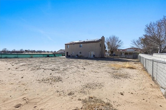 rear view of property with fence, a chimney, and solar panels