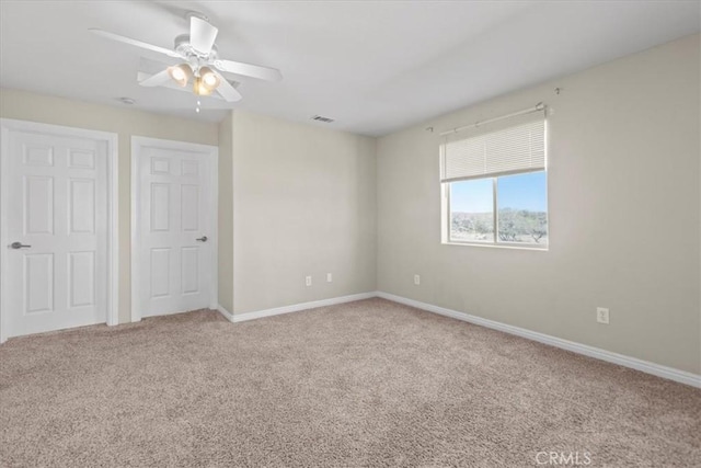 unfurnished bedroom featuring a ceiling fan, visible vents, carpet, and baseboards