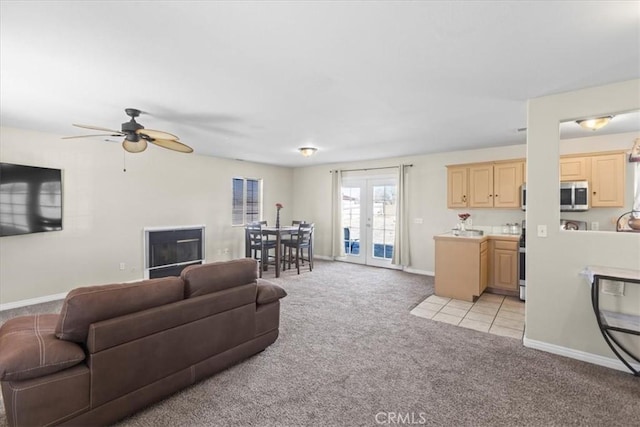 living area featuring baseboards, a ceiling fan, french doors, and light colored carpet