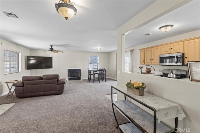 living room featuring baseboards, visible vents, a ceiling fan, and carpet
