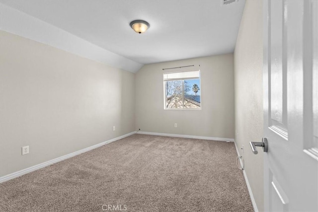 empty room featuring carpet flooring, vaulted ceiling, and baseboards