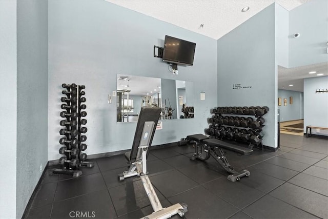 exercise room with baseboards, a high ceiling, and a textured ceiling