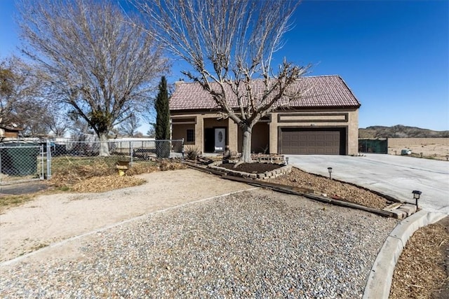 view of front of house with a tile roof, a garage, concrete driveway, stucco siding, and fence