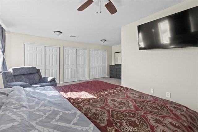 carpeted bedroom featuring visible vents, ceiling fan, and multiple closets