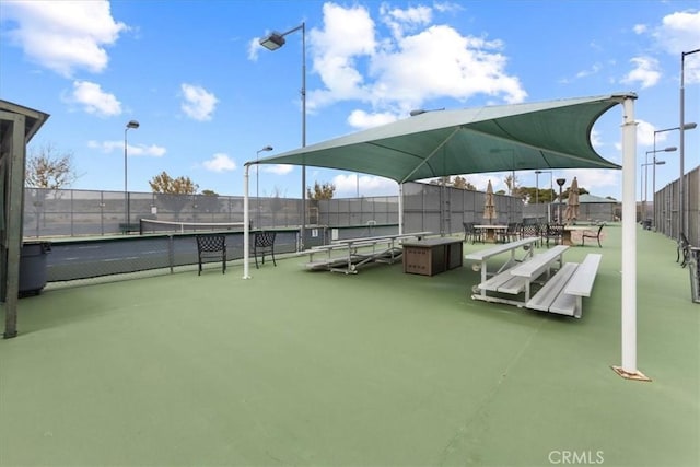view of home's community with a tennis court and fence