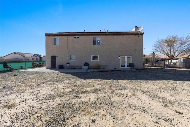 rear view of house with a patio, stucco siding, french doors, and fence