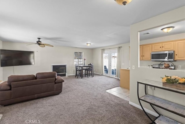 living area featuring carpet, baseboards, visible vents, a ceiling fan, and french doors