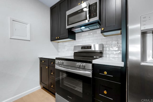 kitchen with light wood finished floors, baseboards, light countertops, decorative backsplash, and stainless steel appliances