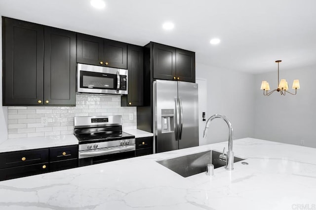 kitchen with tasteful backsplash, decorative light fixtures, dark cabinetry, stainless steel appliances, and a sink