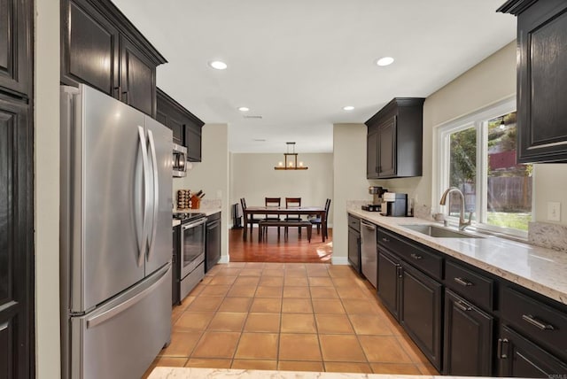 kitchen with light tile patterned floors, recessed lighting, stainless steel appliances, a sink, and decorative light fixtures