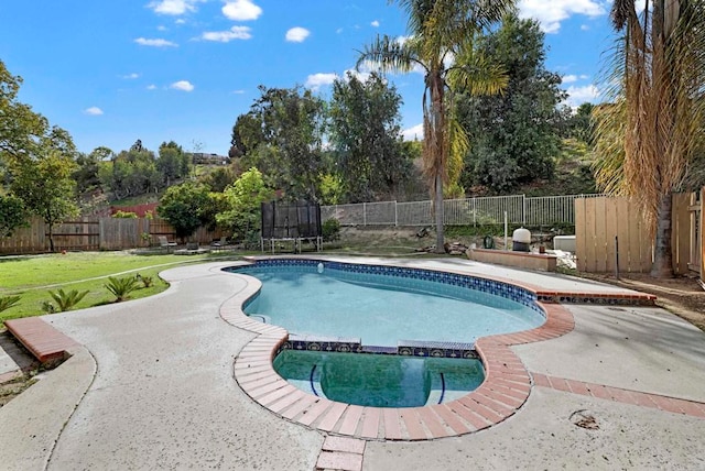 view of pool featuring a fenced backyard, a trampoline, a pool with connected hot tub, and a patio