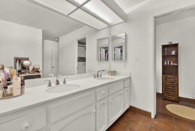 bathroom with double vanity, tile patterned flooring, baseboards, and a sink