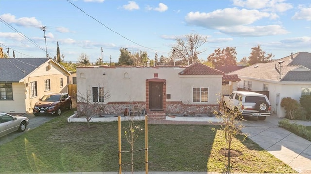 mediterranean / spanish-style house with a front yard, driveway, and stucco siding