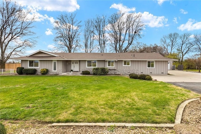 ranch-style home featuring driveway, a front lawn, board and batten siding, and fence