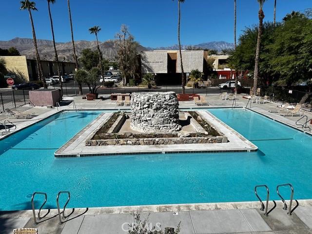 pool featuring a patio, fence, and a mountain view